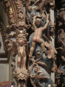 Decorative carvings of a naked cherub climbing a vine.