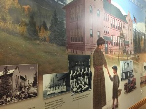 Mural with painting of early twentieth century woman holding young boy's hand in front of building that has become the library in Breckenridge. Mural includes old photographs of a group of students, young male athletes and of the building.
